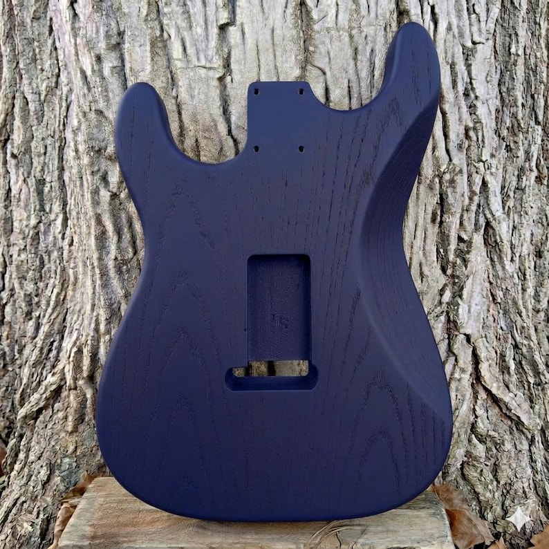 May include: A white ceramic mug with a black handle and the text "But First, Coffee" in a handwritten style. The mug is on a white surface. The mug is approximately 4 inches tall.