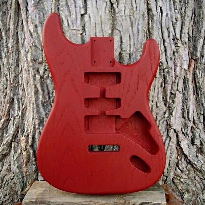 May include: A white ceramic mug with a black handle and the text "But First, Coffee" in a black, handwritten-style font. The mug is on a white surface.