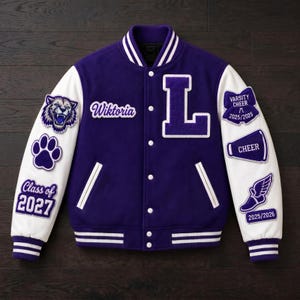 Puede incluir: Una chaqueta universitaria morada y blanca con el nombre Wiktoria, una letra L grande y varios parches que incluyen una cabeza de tigre, una huella, el texto Class of 2027, un megáfono con la palabra Cheer y un zapato alado con 2025/2026.