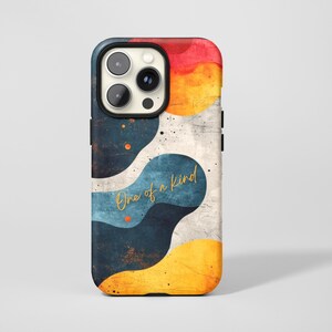 May include: A phone case with an abstract design in red, yellow, and blue. The case has the gold text "One of a kind". The phone case has a black camera cutout. The design has a textured, distressed appearance.