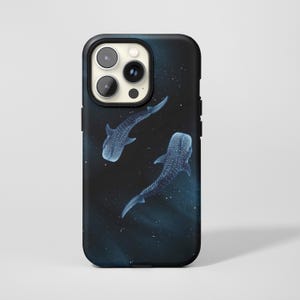 Könnte beinhalten: Eine schwarze Smartphone-Hülle mit einem grafischen Design von zwei Walhaien, die durch eine dunkle, tiefblaue Meeresumgebung schwimmen, mit verstreuten weißen Punkten, die an Lichtreflexionen im Wasser oder einen Sternenhimmel erinnern.