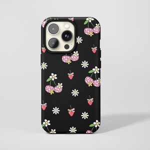 Könnte beinhalten: Schwarze Handyhülle mit einem sich wiederholenden Muster aus rosa Kirschen, weißen Gänseblümchen und roten Erdbeeren mit rosa Schleifen. Die Kirschen haben ein rosa Vichy-Muster. Die Hülle hat eine schwarze Kameralinsenabdeckung.