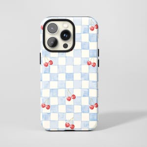 Op de afbeelding: Telefoonhoesje met een blauw en wit geblokt patroon met roodkleurige kersen in aquarel. De hoes heeft een zwarte rand rond de camera en een glanzende afwerking.
