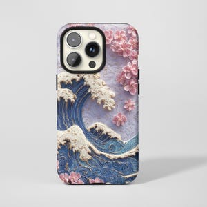 Könnte beinhalten: Eine Handyhülle mit einem 3D-Design einer japanischen Welle mit weißen Kämmen und blauem Wasser. Rosa Kirschblüten sind auf einem lavendelfarbenen Hintergrund verstreut. Die Hülle hat einen schwarzen Kameraausschnitt.
