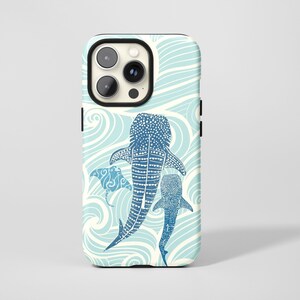 May include: A phone case featuring a blue and white design with a whale shark and a manta ray swimming in a sea of waves. The case has a black border and a glossy finish. The design is detailed and artistic.