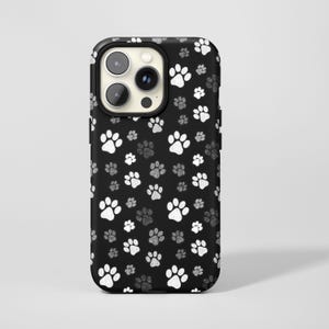 May include: Black phone case with a pattern of white and gray paw prints. The case has a black border and a camera cutout. The paw prints vary in size and are scattered across the surface of the case.