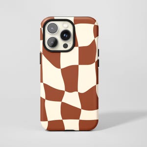 May include: A phone case with a brown and cream-colored wavy checkerboard pattern. The case has a black camera lens border and black side buttons. The design covers the entire back of the phone case.