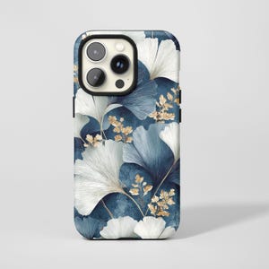 May include: A smartphone case featuring a botanical design. The case has a dark blue background with a pattern of white and blue ginkgo leaves and gold accents. The case has a black border and a camera cutout.