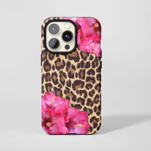 Könnte beinhalten: Eine Handyhülle mit Leopardenmuster und zwei leuchtend rosa Hibiskusblüten. Die Hülle hat einen schwarzen Rand und einen Kameraausschnitt.