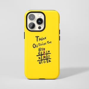 Könnte beinhalten: Gelbe Handyhülle mit schwarzem Rand. Auf der Hülle steht der Text "THINK OUTSIDE THE BOX" über einem Tic-Tac-Toe-Spiel mit einer roten Linie in der Mitte.