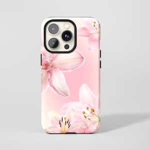 May include: A phone case featuring a floral design with pink lilies against a soft pink gradient background. The case has a black border around the camera and sides, and a white interior.