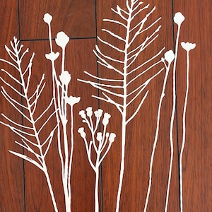 May include: White botanical illustrations of various plants and flowers are displayed against a rich, dark brown wood grain background. The design features delicate lines and shapes, creating a minimalist and natural aesthetic.