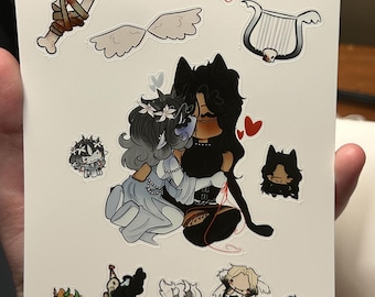 Op de afbeelding: Een witte stickervel met verschillende cartoon illustraties. De hoofdafbeelding toont twee figuren die elkaar omarmen, omringd door kleinere afbeeldingen van vleugels, een lier, een dolk en andere karakterontwerpen. Het kunstwerk heeft een fantasiethema.