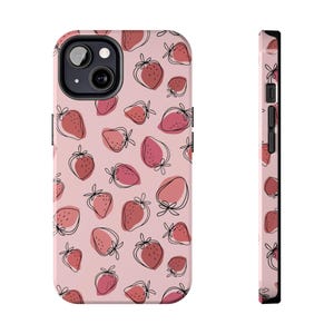 May include: A pink phone case featuring a repeating pattern of strawberries in shades of red and pink with black outline details. The case has a black border and a camera cutout.