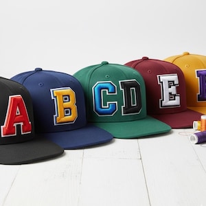 Two color varsity style 3D puff embroidery on cap with bold athletic college lettering in raised foam stitch