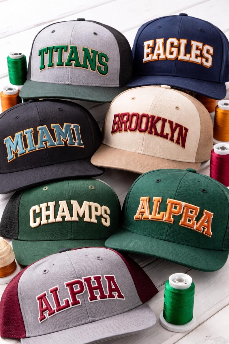 Multiple snapback hats featuring different color combinations of 3D puff varsity embroidery font styles