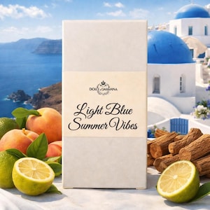May include: A rectangular box with the text "Light Blue Summer Vibes" and the Dolce & Gabbana logo. The image features peaches, lemons, and a scenic background of a blue sea and white buildings with blue domes.