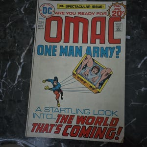 May include: A vintage comic book cover for OMAC, featuring a dynamic illustration of a superhero in action. The cover has bold red and blue lettering, with the title "OMAC" prominently displayed. The comic is marked as the 1st Spectacular Issue and priced at 20¢.