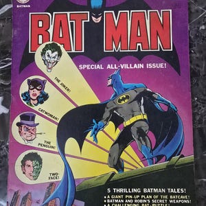 Puede incluir: Una portada de cómic de Batman vintage. La portada presenta a Batman en una pose dinámica, con el título "BATMAN" en letras grandes y en negrita. La portada también incluye imágenes de villanos como The Joker, Catwoman, The Penguin y Two-Face. Es un "Special All-Villain Issue!"