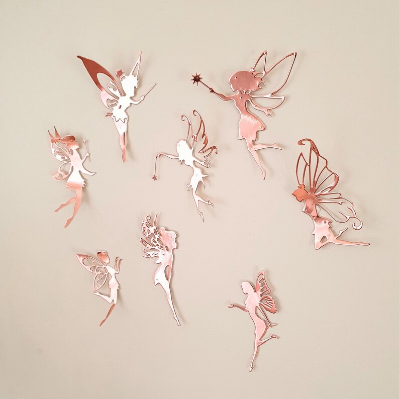 Pu&ograve; includere: Una collezione di otto decorazioni murali a forma di fata in oro rosa in varie pose. Ogni fata ha ali dettagliate ed &egrave; tagliata da un metallo riflettente. Alcune fate tengono bacchette, il tutto su uno sfondo neutro.