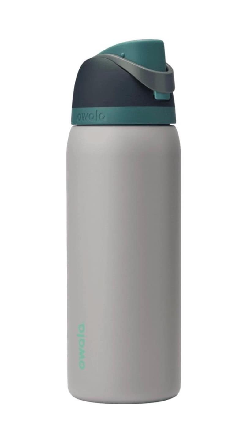 May include: A gray water bottle with a teal and navy blue lid. The bottle has the word "owala" printed on it in teal. The bottle is cylindrical and appears to be made of metal.