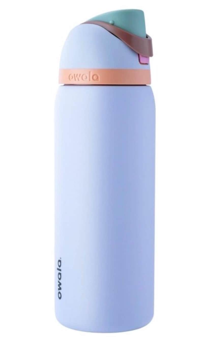 May include: A light blue Owala water bottle with a teal and brown lid. The bottle has a peach-colored band around the middle and the word "owala" is printed on the bottle. The bottle is designed to keep drinks cold.