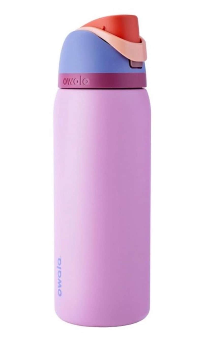 May include: A lavender-colored Owala water bottle with a multi-colored lid. The lid features a blue top, a peach-colored hinge, and a red spout. The Owala logo is printed on the bottle and lid.