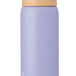 May include: A lavender-colored Owala water bottle with a light blue lid and a tan accent. The bottle has the brand name "owala" printed on the side. The lid has a gray handle and a push-button opening mechanism.