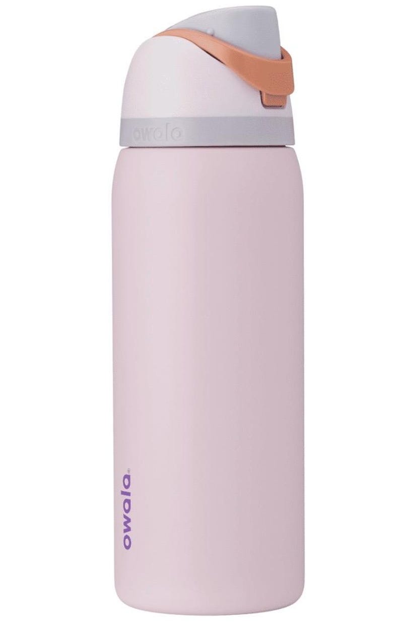 May include: A light pink Owala water bottle with a gray and white lid and a tan handle. The bottle has a cylindrical shape and the brand name is printed in purple on the side.