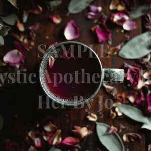 May include: Overhead view of a cup of dark red liquid, possibly tea or a potion, with a gray handle, surrounded by dried rose petals and green leaves. The text "Mystic Apothecary Kit" and "Her By Jo" is visible.