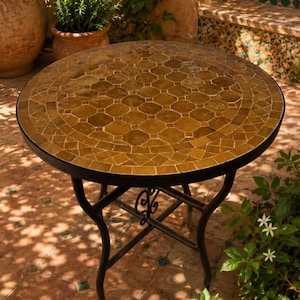 Peut inclure: Une table ronde dotée d'un plateau en mosaïque composé de carreaux bruns hexagonaux et en forme de losange. La table est soutenue par un cadre en métal noir avec quatre pieds incurvés reliés par une structure en croix avec un détail décoratif.
