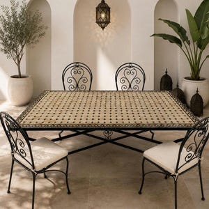 May include: A rectangular dining table with a beige and black geometric tiled top and a black metal frame, accompanied by four black metal chairs featuring scrollwork backrests and off-white seat cushions, arranged in a symmetrical dining set.