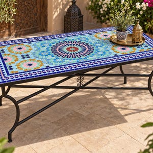 May include: A rectangular outdoor table featuring a vibrant mosaic tile top with intricate geometric patterns in shades of blue, turquoise, pink, and yellow. The table is supported by a black metal frame with curved legs and a cross-brace design.