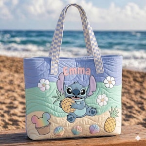 May include: A quilted tote bag with a cartoon character holding a pineapple. The bag has a light blue background with a wave pattern, white flowers, and the name "Emma". The handles and top trim have a checkered pattern.