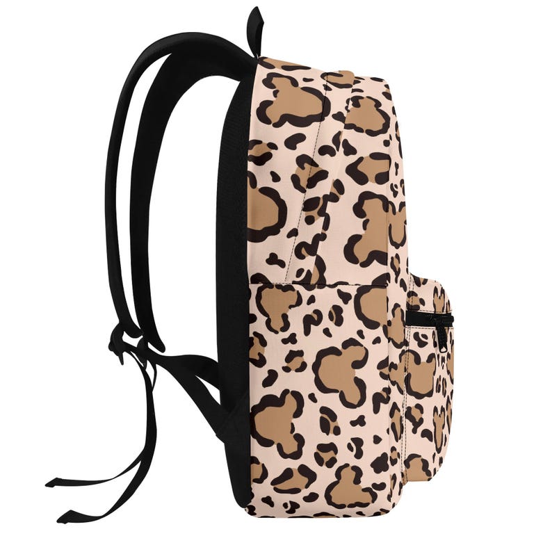 May include: A backpack featuring a light beige base with a repeating animal print pattern composed of tan shapes outlined in black. The bag includes black shoulder straps, a black zipper on the front pocket, and a black handle at the top.