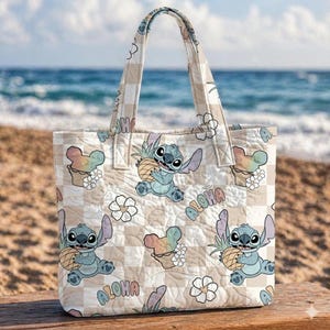 Pu&ograve; includere: Borsa tote a quadri beige e bianca con un personaggio dei cartoni animati che tiene in mano un ananas. La borsa ha un design floreale e gelato arcobaleno, con la parola "Aloha" stampata sul davanti. La borsa ha un manico.