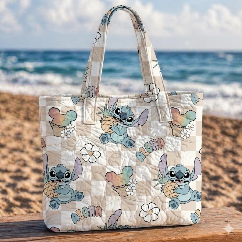 Pu&ograve; includere: Borsa tote a quadri beige e bianca con un personaggio dei cartoni animati che tiene in mano un ananas. La borsa ha un design floreale e gelato arcobaleno, con la parola "Aloha" stampata sul davanti. La borsa ha un manico.