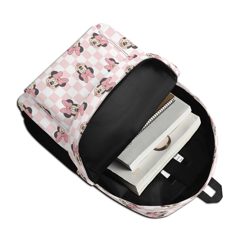 Peut inclure: Un sac &agrave; dos avec un compartiment principal ouvert pr&eacute;sentant un motif &agrave; carreaux rose clair et blanc orn&eacute; de visages de Minnie Mouse r&eacute;p&eacute;t&eacute;s. &Agrave; l'int&eacute;rieur doubl&eacute; de noir, deux cahiers blancs &agrave; reliure spirale sont empil&eacute;s.