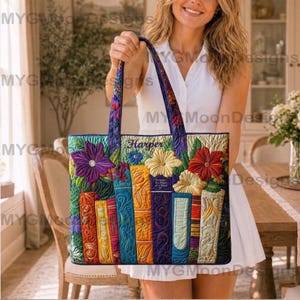 Könnte beinhalten: Eine farbenfrohe Tragetasche mit Blumen- und Buchdesign. Die Tasche hat gestickte Blumen in Lila, Gelb und Rot sowie eine Reihe von Büchern in verschiedenen Farben. Der Name "Harper" ist oben eingestickt. Die Tasche hat einen lila Griff.