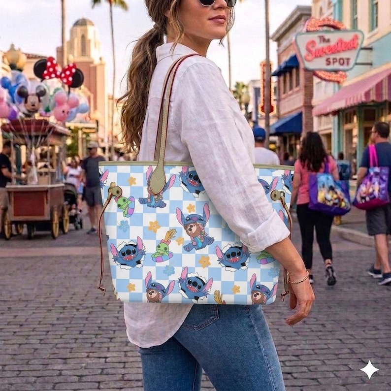 May include: A light blue and white tote bag featuring a checkered pattern with cartoon characters. The bag has brown handles and a light blue interior. The bag is being carried on a brick-paved street.