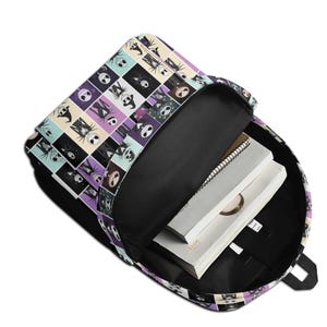May include: A backpack with an open main compartment featuring a grid pattern of various character illustrations from The Nightmare Before Christmas. The interior is black and contains a spiral-bound notebook and a white book with the year 2012 printed.