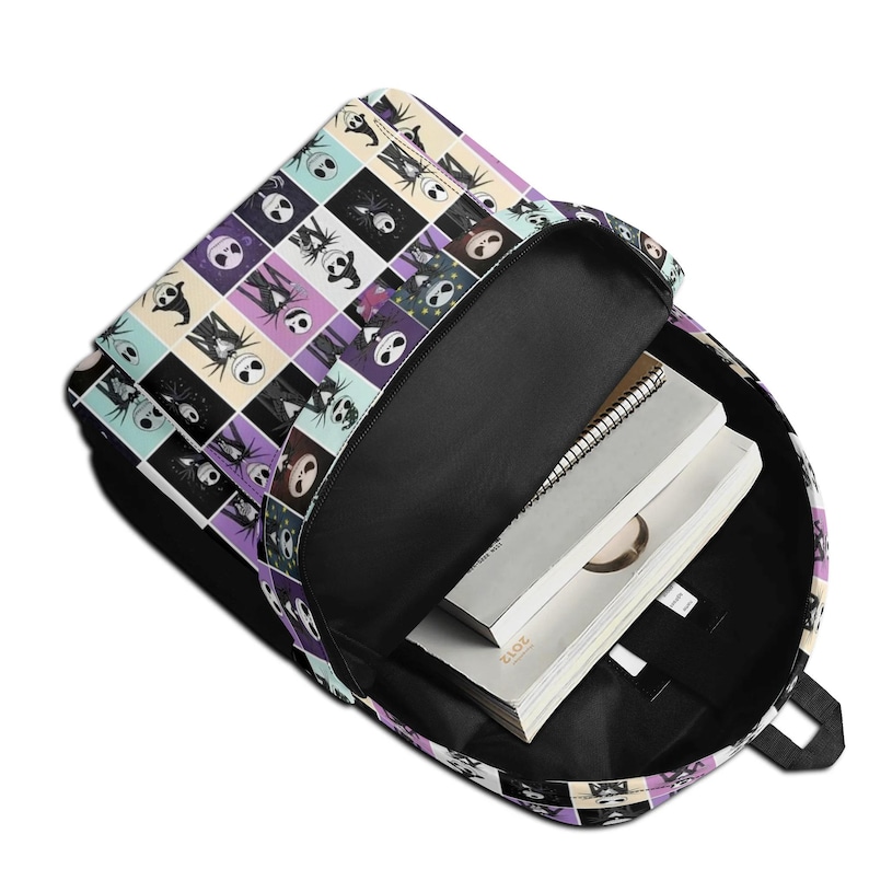 May include: A backpack with an open main compartment featuring a grid pattern of various character illustrations from The Nightmare Before Christmas. The interior is black and contains a spiral-bound notebook and a white book with the year 2012 printed.