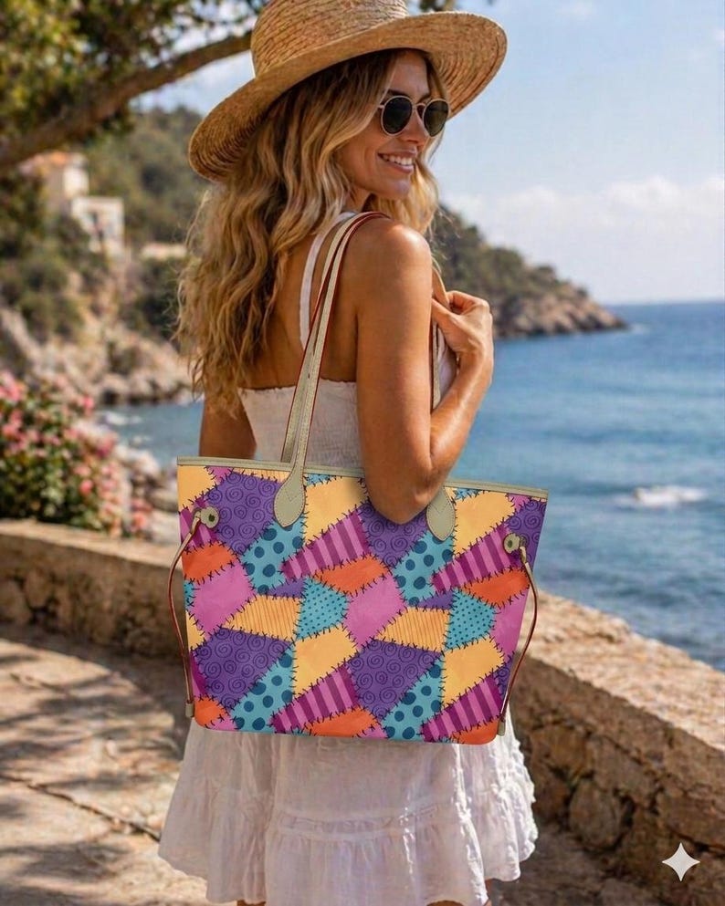 May include: A tote bag featuring a colourful patchwork pattern of purple, orange, yellow, and blue sections with various prints including swirls, stripes, and polka dots, held by two light-coloured shoulder straps with metallic hardware accents.