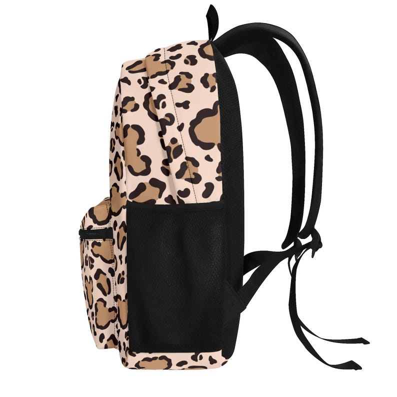 May include: A backpack featuring a light beige base with a brown and black leopard print pattern. The bag includes a front zippered pocket, a black mesh side pocket, black adjustable shoulder straps, and a black top handle for carrying.