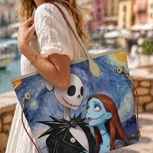 Puede incluir: Un bolso tote con una ilustraci&oacute;n impresa de Jack Skellington y Sally sobre un fondo azul de noche estrellada. El bolso tiene asas de color claro con bordes rojos y herrajes met&aacute;licos en los laterales para sujetar las correas.