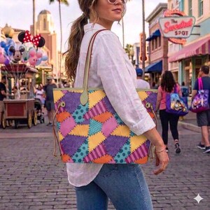 May include: A tote bag featuring a colourful patchwork pattern of purple, orange, teal, and pink triangles. The design includes various textures like polka dots, stripes, and swirls. The bag has two thin shoulder straps and gold-toned hardware.