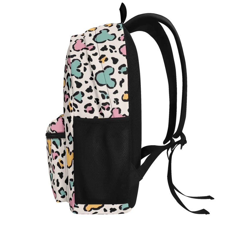 K&ouml;nnte beinhalten: Ein Rucksack mit cremefarbener Basis und einem sich wiederholenden Tiermuster in Rosa, T&uuml;rkis und Gelb, durchsetzt mit schwarzen Flecken und Mausohr-Silhouetten. Er verf&uuml;gt &uuml;ber eine seitliche Netztasche in Schwarz sowie schwarze Trageriemen.