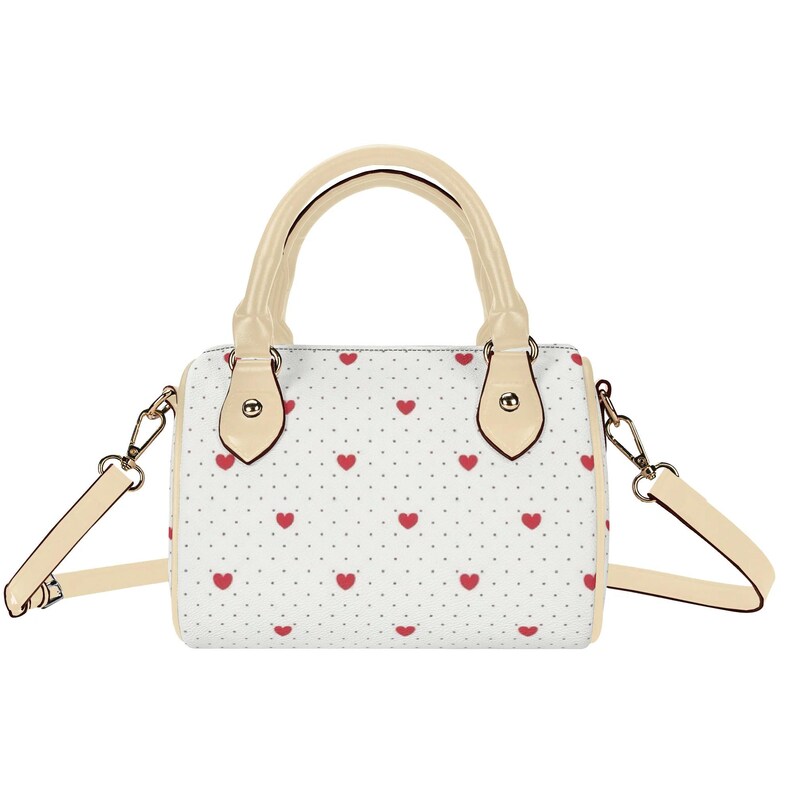May include: A white handbag with a pattern of small red hearts and gray dots. The bag has a cream-colored handle and shoulder strap. The hardware is gold-colored.