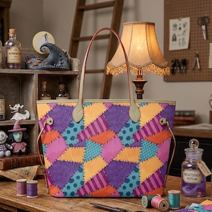 May include: A tote bag featuring a colourful patchwork design with purple, orange, pink, and teal sections. The pattern includes swirls, stripes, and polka dots. The bag has two thin, light-coloured shoulder straps attached with metal hardware.