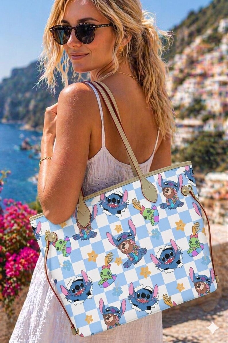 May include: A light blue and white tote bag featuring a checkered pattern with cartoon character graphics. The bag has tan handles and red side straps. The bag is being held by a person wearing sunglasses and a white dress.